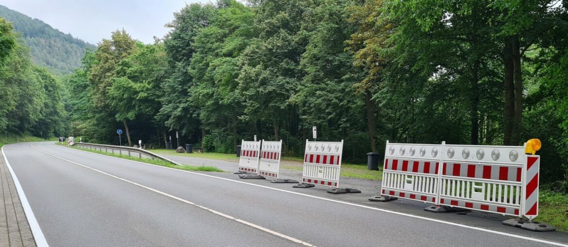 Straßensperre auf einer Landstraße mit Bäumen im Hintergrund.