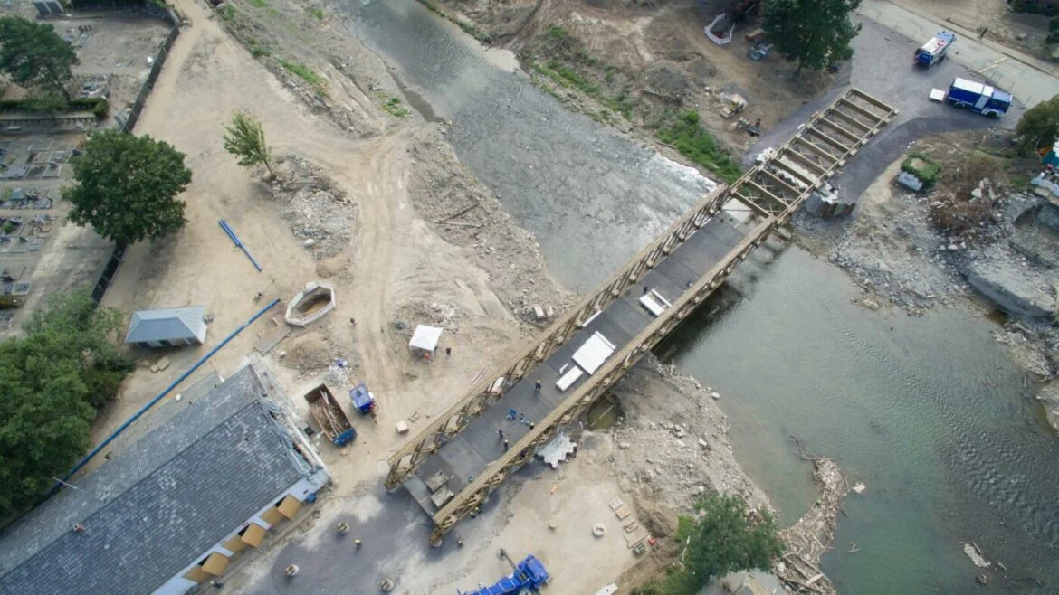 Luftbild der Ahrtorbrücke im Bau, umgeben von Fluss und Baustelle.