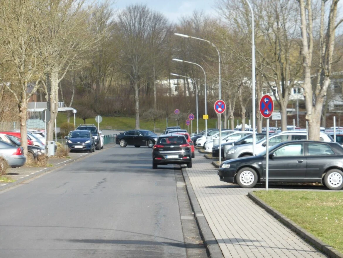 Parkplatz am Schulzentrum mit Autos und Verkehrsschildern.