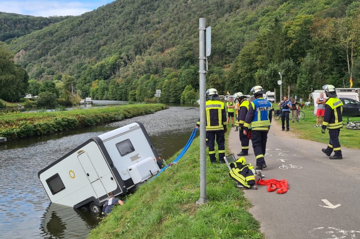 Feuerwehrleute bergen Wohnwagen aus Flussufer.