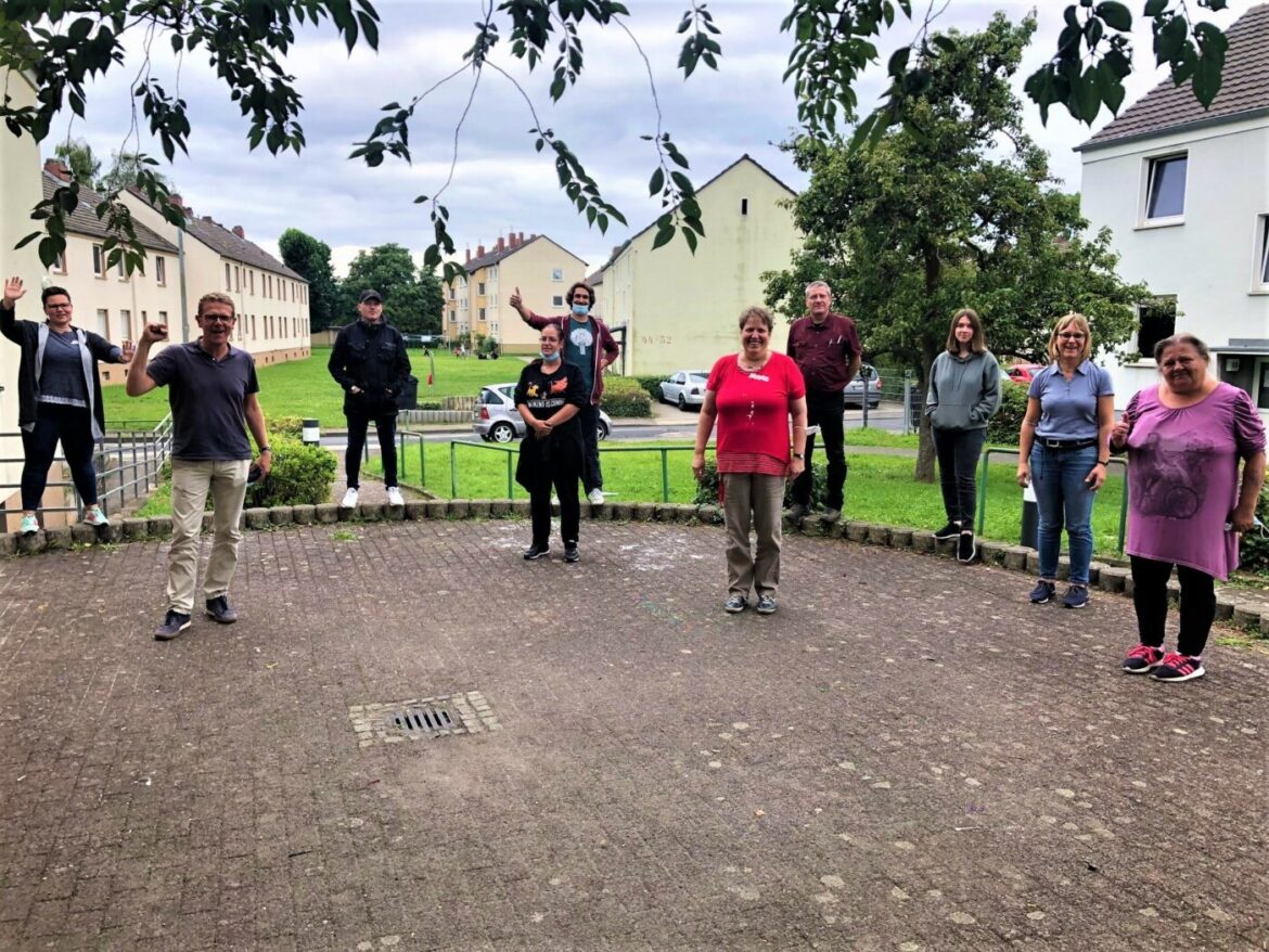 Gruppe von Menschen steht draußen in einem Halbkreis.