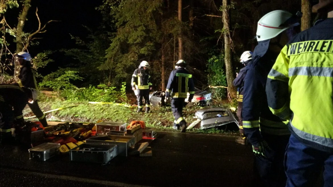 Feuerwehrleute bei einem nächtlichen Einsatz an einem Unfallort im Wald.
