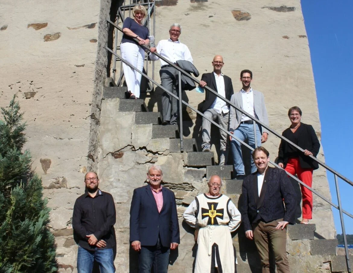Gruppe von Menschen auf einer Treppe vor einer Burgmauer.