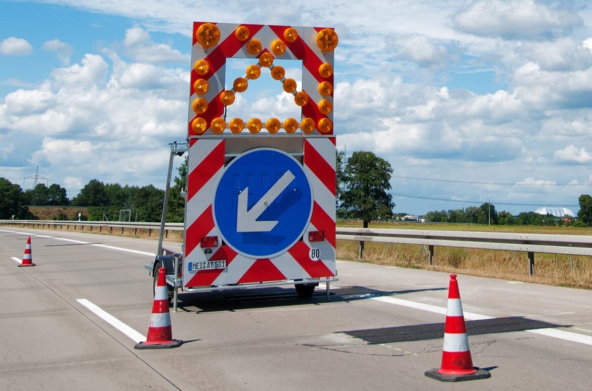 Warnschild auf Autobahn mit Pfeil nach links.