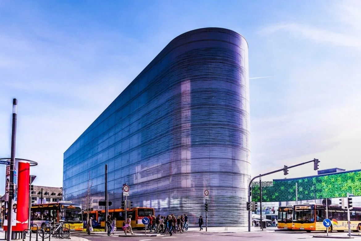 Modernes Gebäude in Koblenz mit Glasfassade und vorbeifahrenden Bussen.