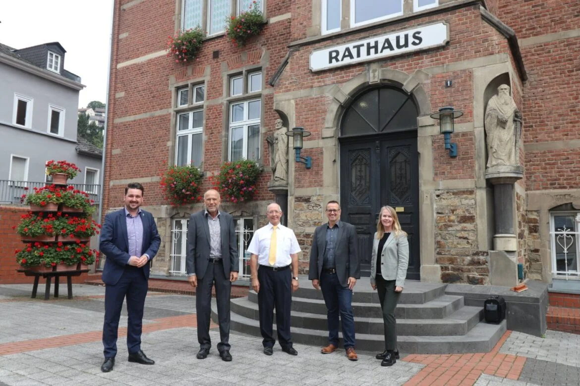 Fünf Personen stehen vor einem historischen Rathausgebäude.