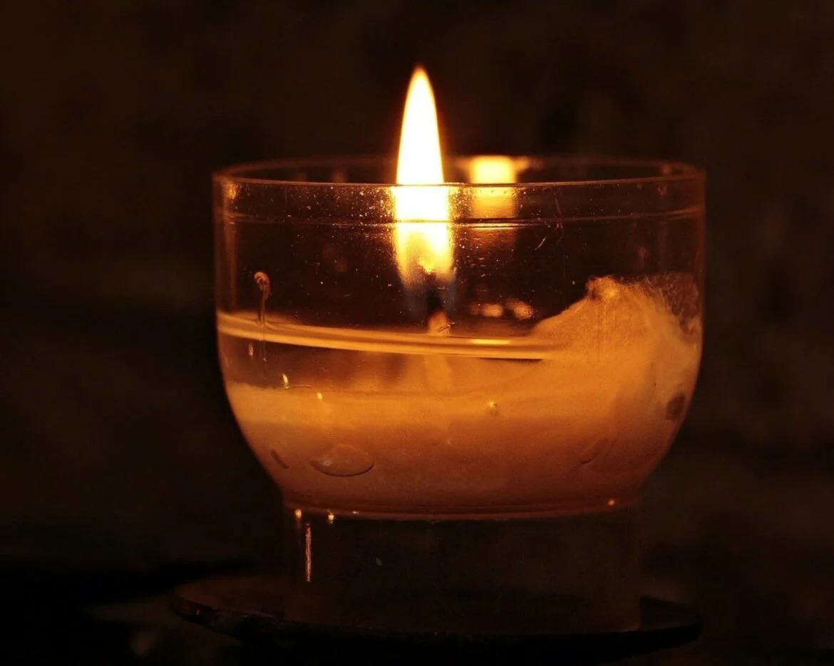 Ein brennendes Teelicht in einem dunklen Raum.