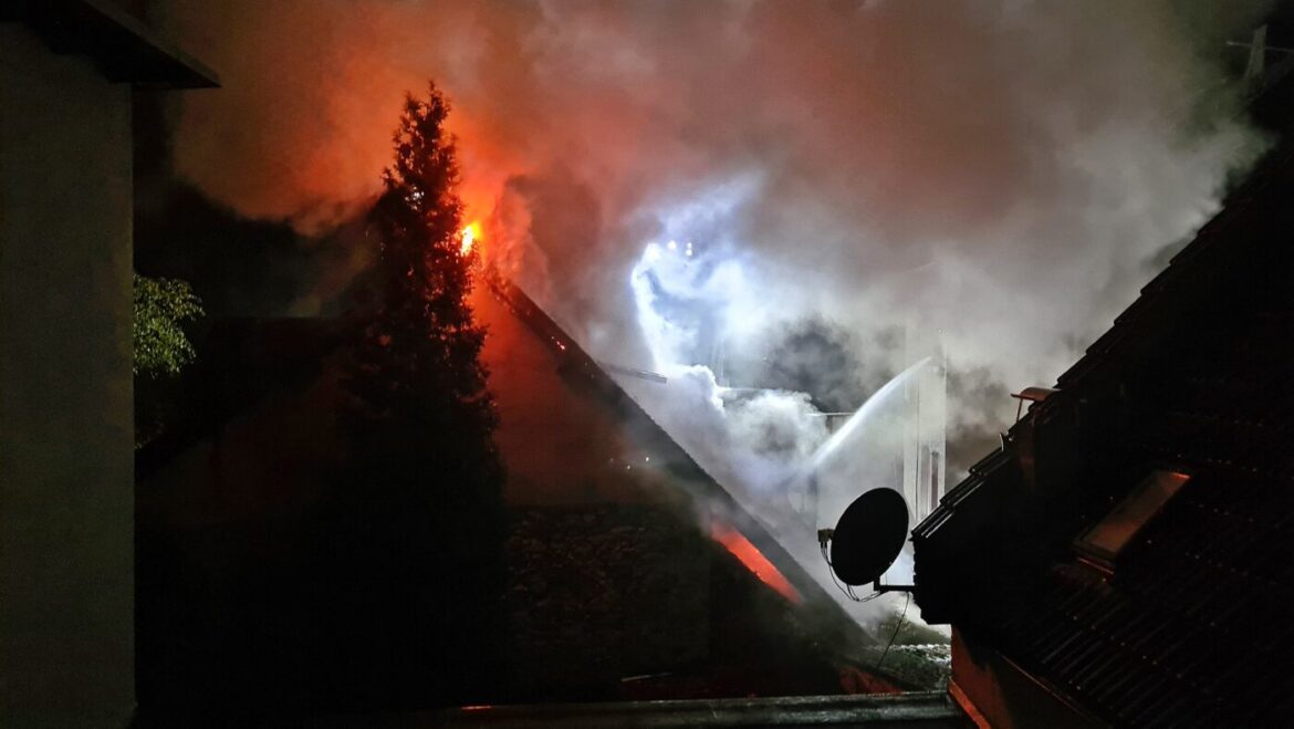 Nächtlicher Brand in einem Gebäude mit Feuerwehr im Einsatz.