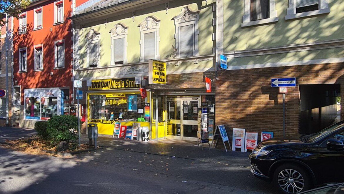 Geschäftsfassade mit gelbem Schild und Werbetafeln.