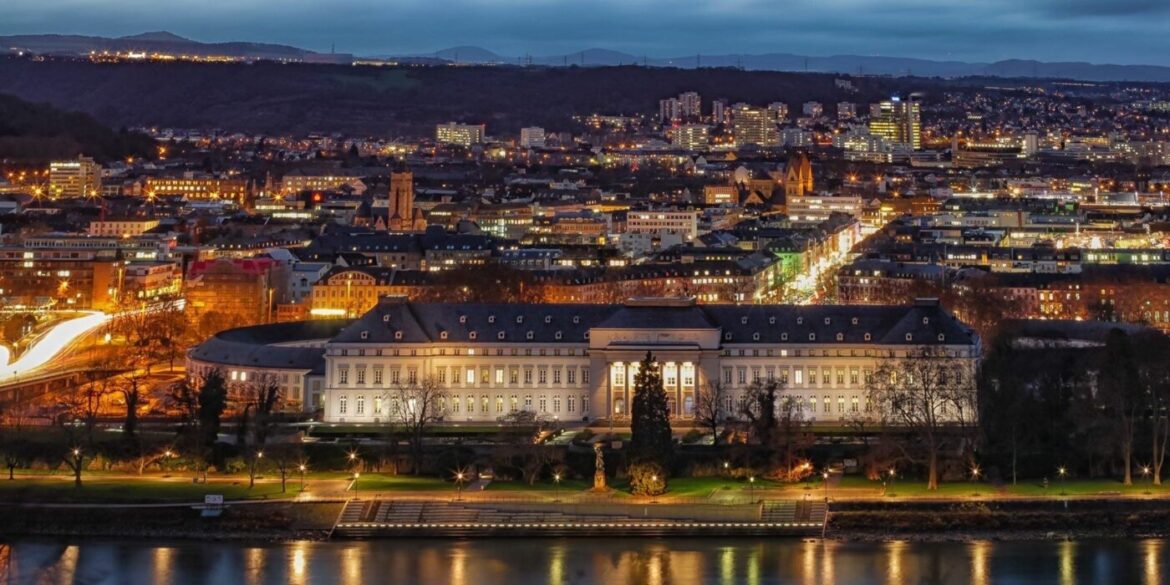 Nächtliche Stadtansicht mit beleuchteten Gebäuden und Fluss im Vordergrund
