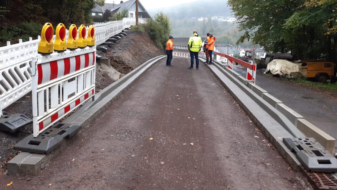 Bauarbeiten an einer Gemeindestraße mit Arbeitern und Absperrungen.