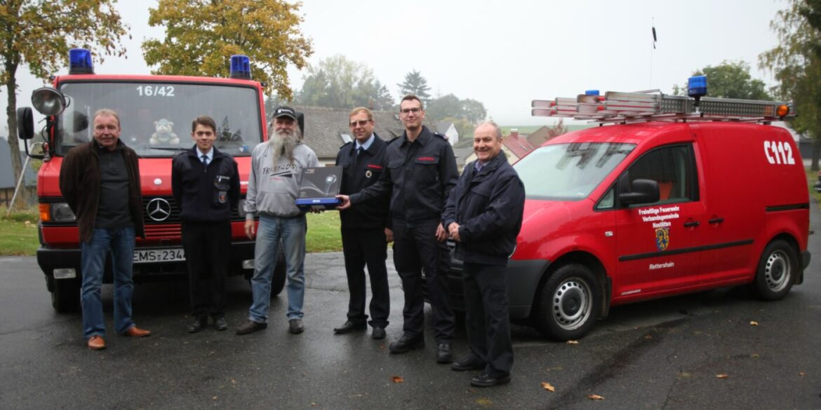 Gruppe von Menschen vor zwei roten Feuerwehrfahrzeugen.