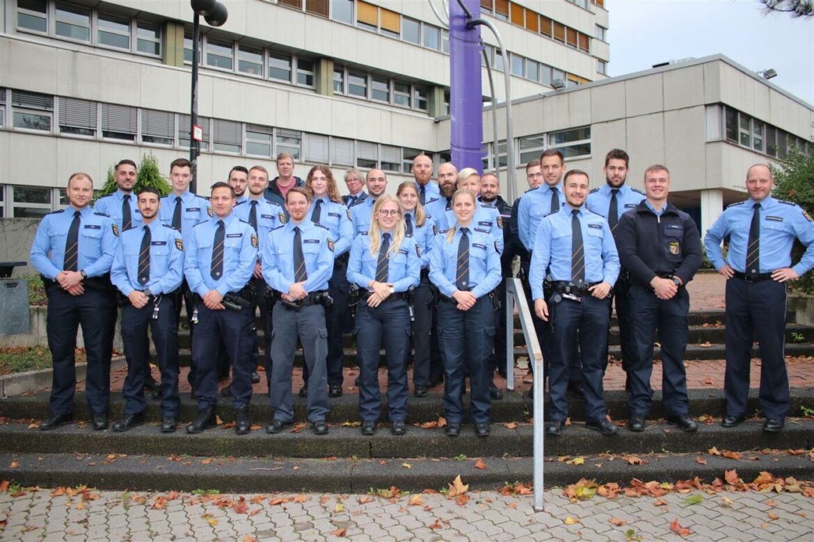Gruppe neuer Beamter in blauen Uniformen vor einem Gebäude.