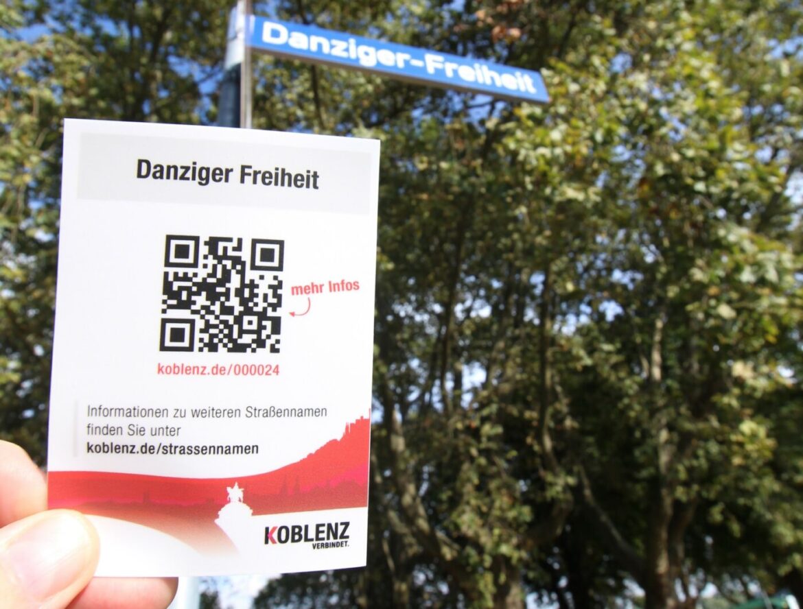 QR-Code auf einem Schild vor einem Straßenschild mit der Aufschrift Danziger Freiheit.