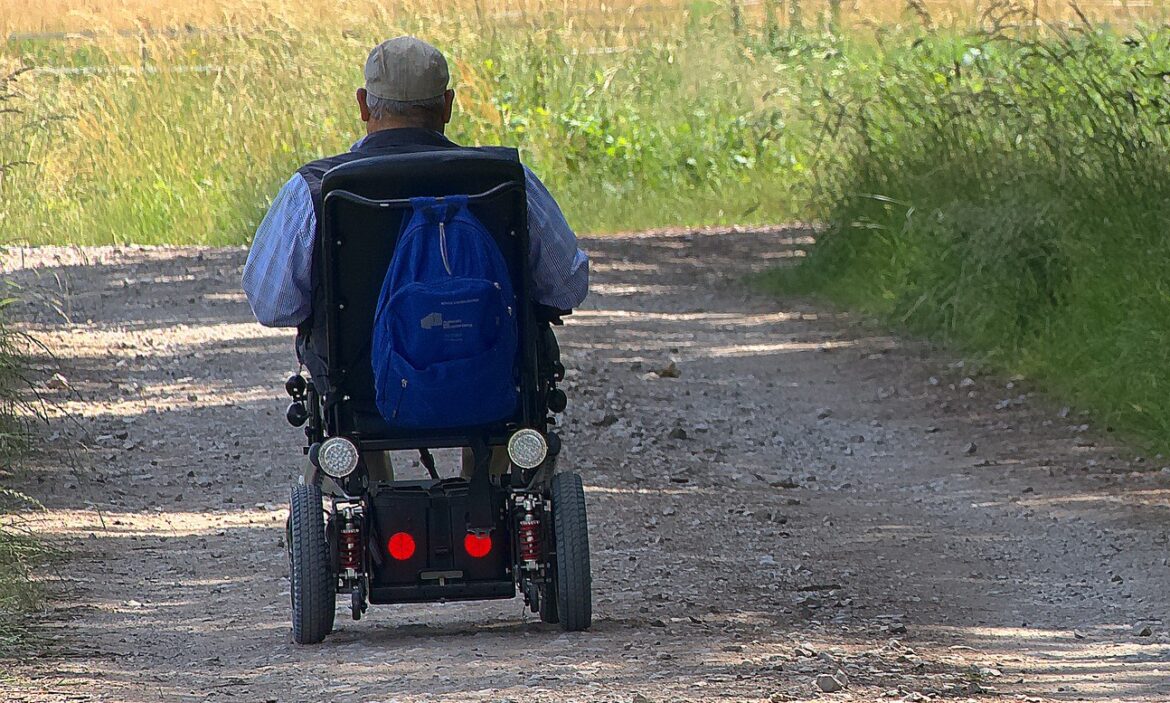 Senior im Rollstuhl auf einem ländlichen Weg