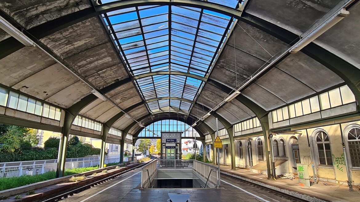 Historischer Bahnhof mit Glasdach und Gleisen.