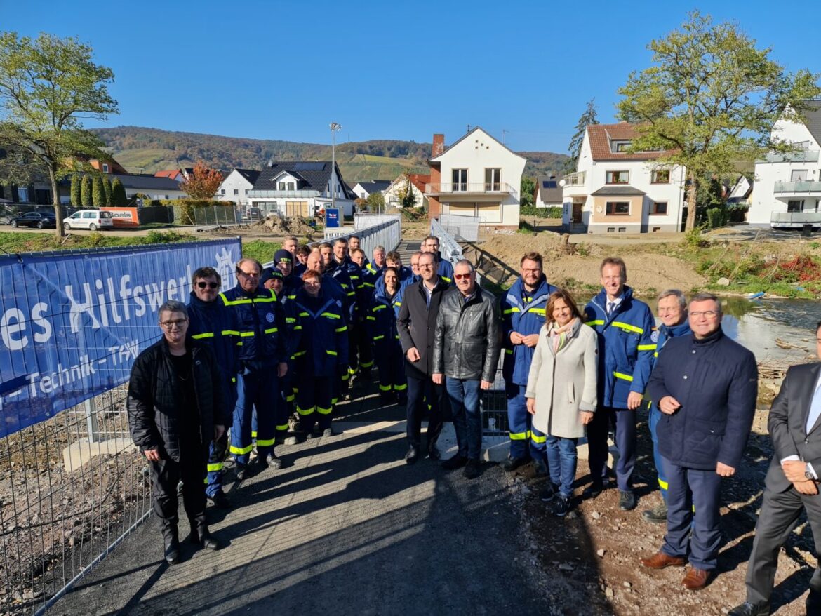 Gruppe von Menschen in blauer Uniform vor einem Bauzaun.