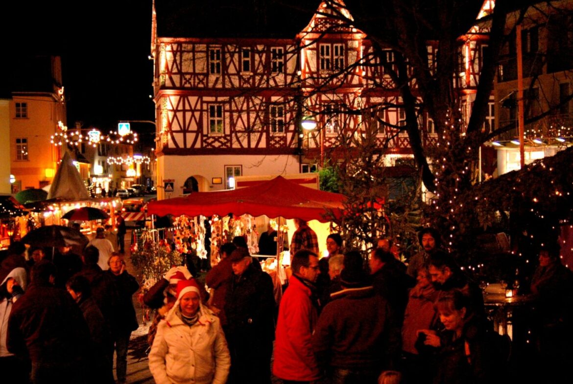 Menschenmenge auf einem Weihnachtsmarkt in Nassau bei Nacht.