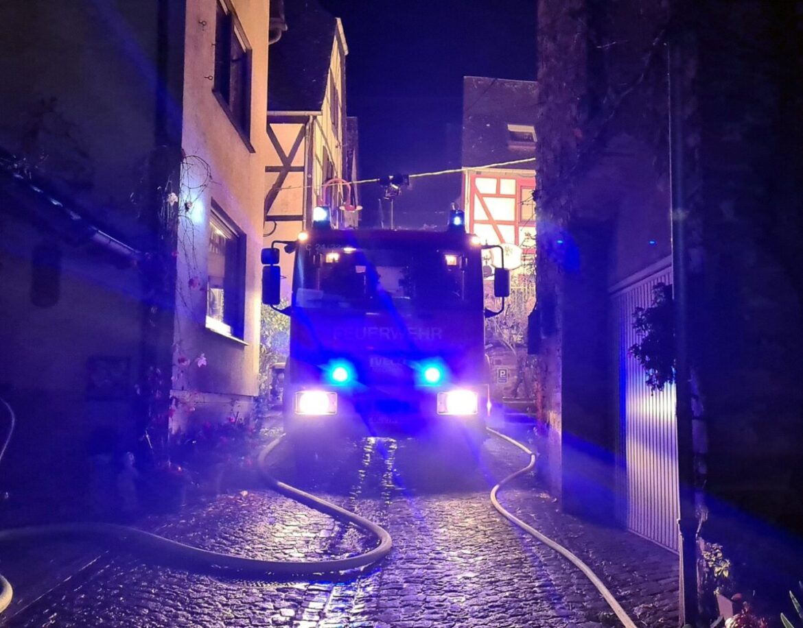 Feuerwehrauto in einer engen Gasse bei Nacht mit blauen Lichtern