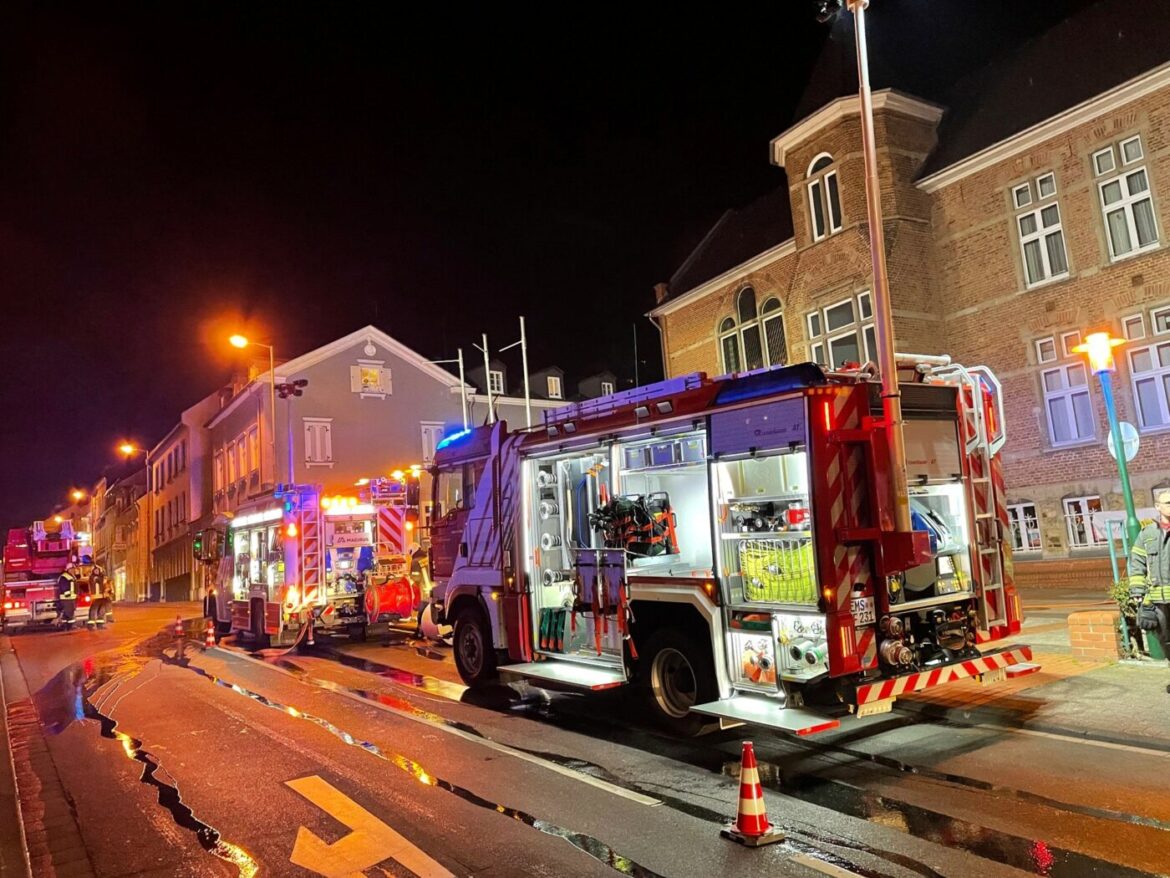Feuerwehrfahrzeuge bei Nacht vor einem Rathaus im Einsatz.