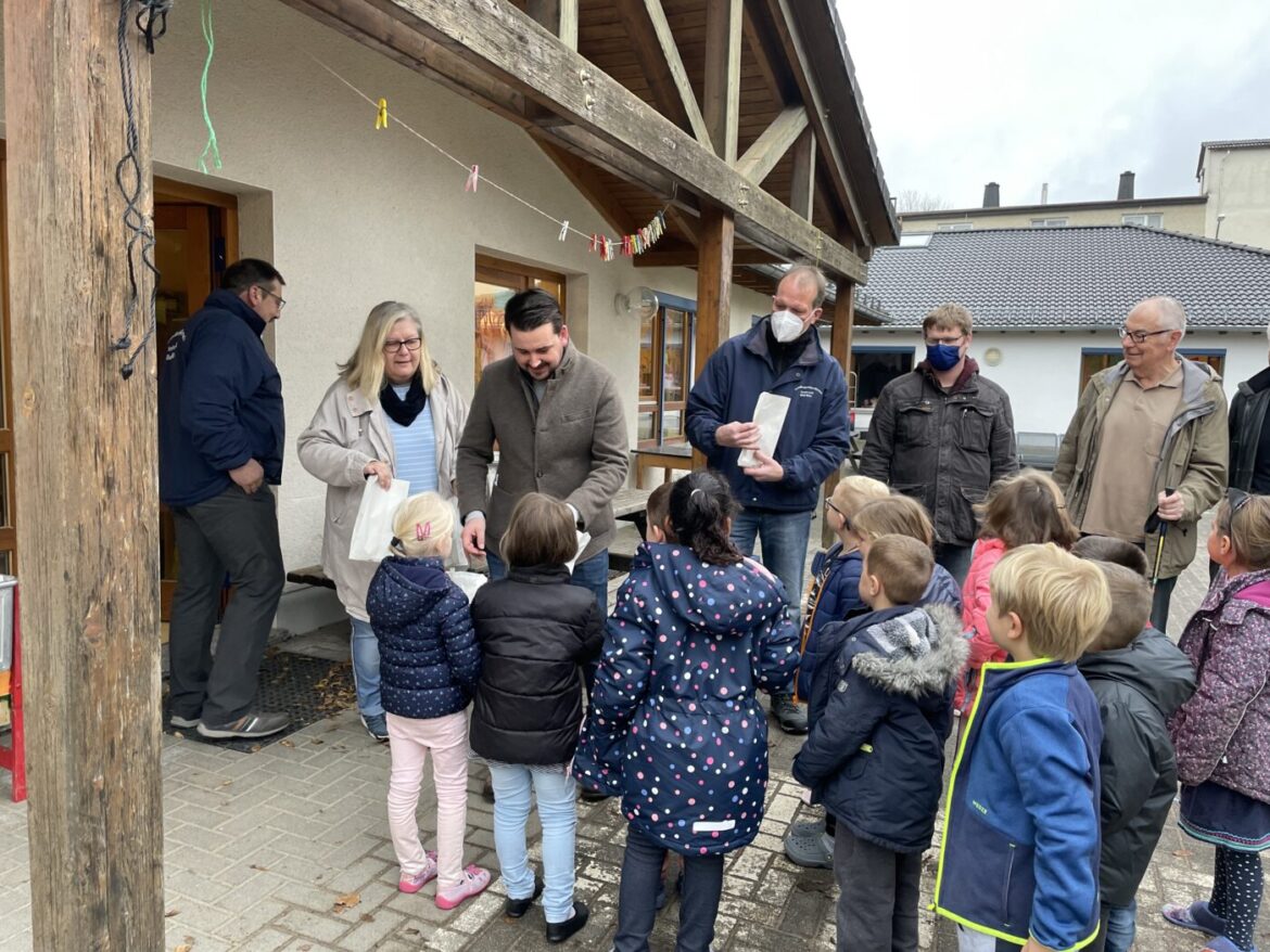 Gruppe von Menschen, darunter Kinder, vor einem Gebäude versammelt.
