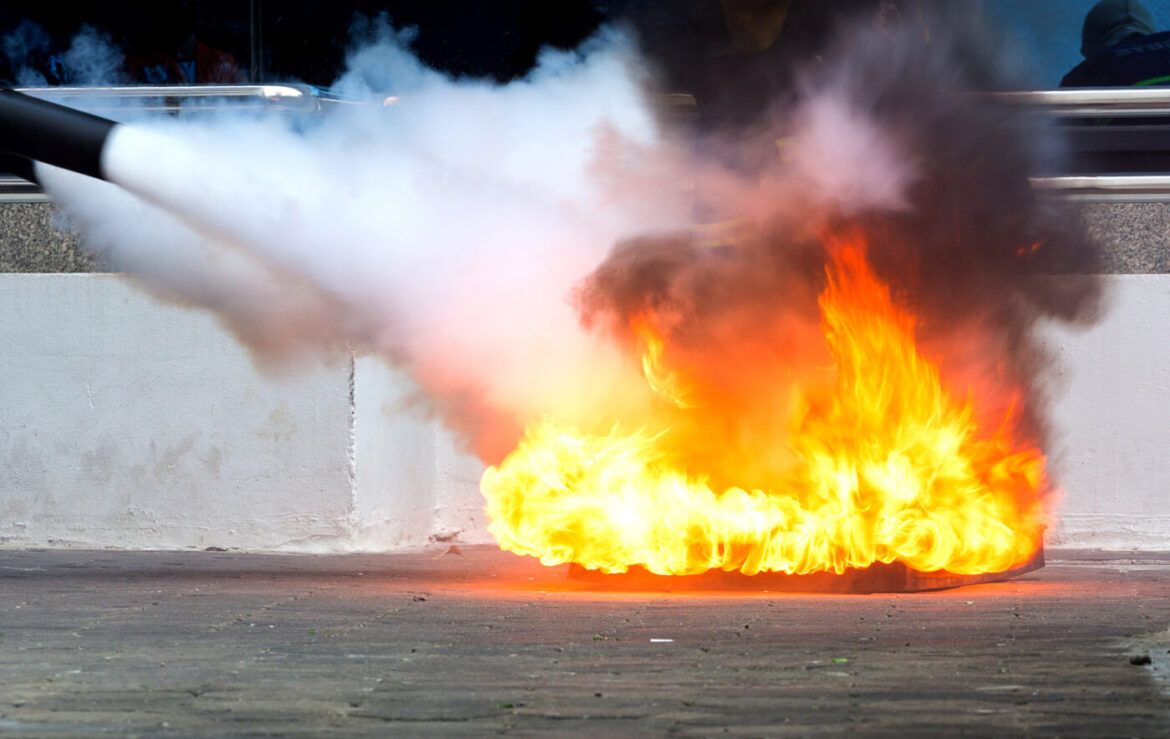 Feuerlöscher löscht brennendes Feuer auf dem Boden