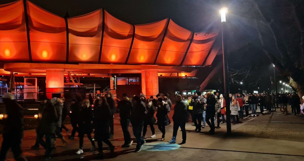 Menschenmenge bei Nacht vor einem beleuchteten Gebäude.