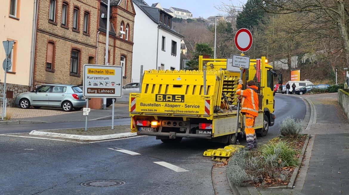 Arbeiter sichern eine Baustelle auf einer Straße ab.