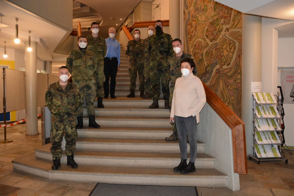 Gruppe von Personen in Uniform und Zivilkleidung auf einer Treppe.