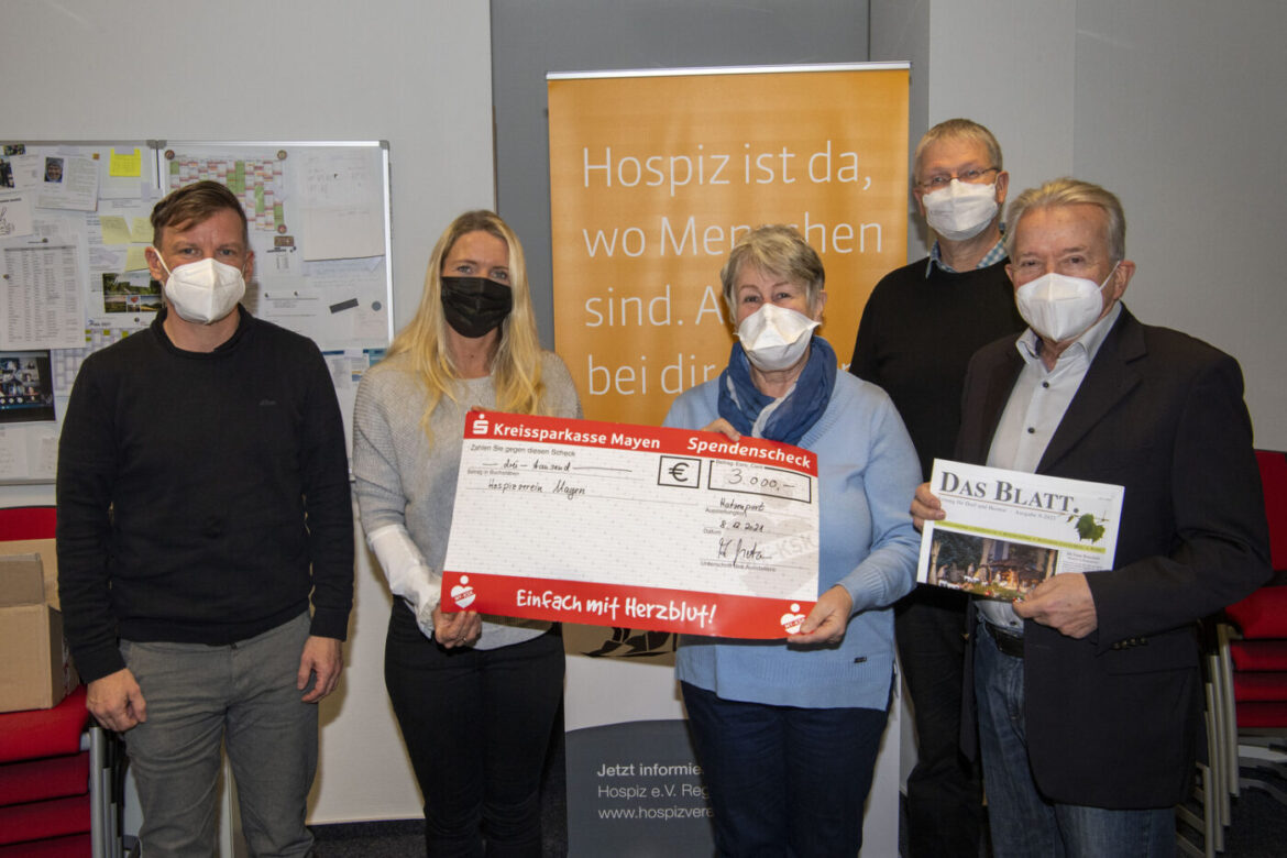 Gruppe von fünf Personen mit einem großen Scheck und einer Zeitung.