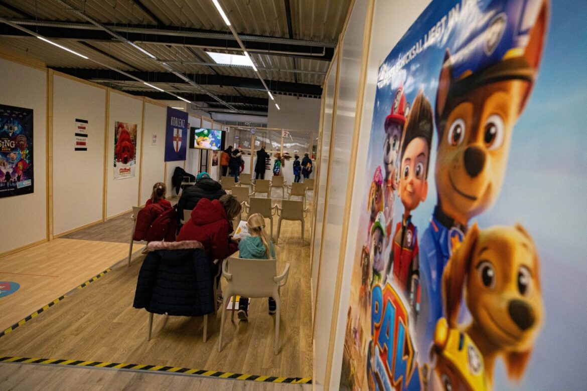 Wartebereich mit Menschen und Filmplakaten an der Wand.