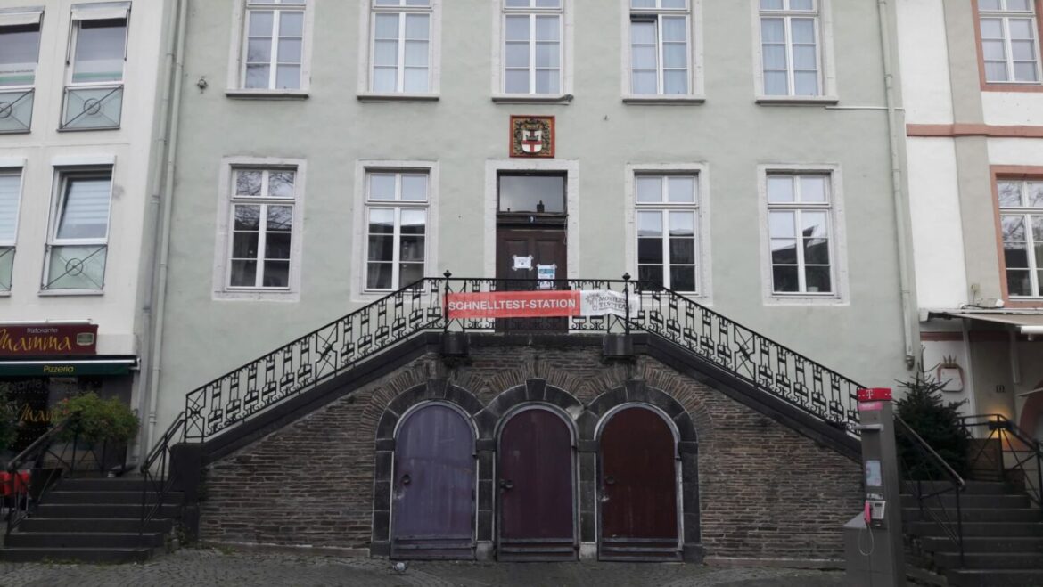 Eingang zu einem Gebäude mit Schild 'Schnellteststation' über der Treppe.