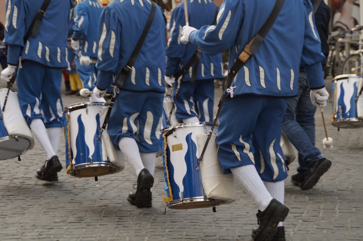 Trommler in blauen Uniformen marschieren auf Kopfsteinpflaster