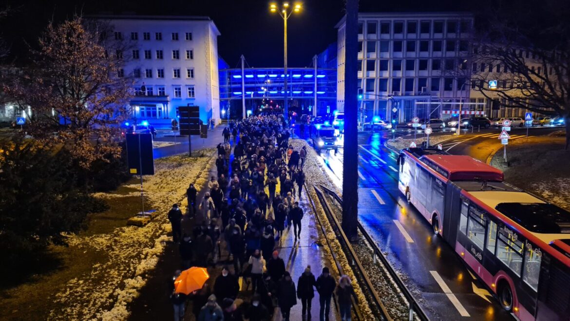 Menschenmenge bei Nacht auf einer Straße mit Bus und Lichtern.