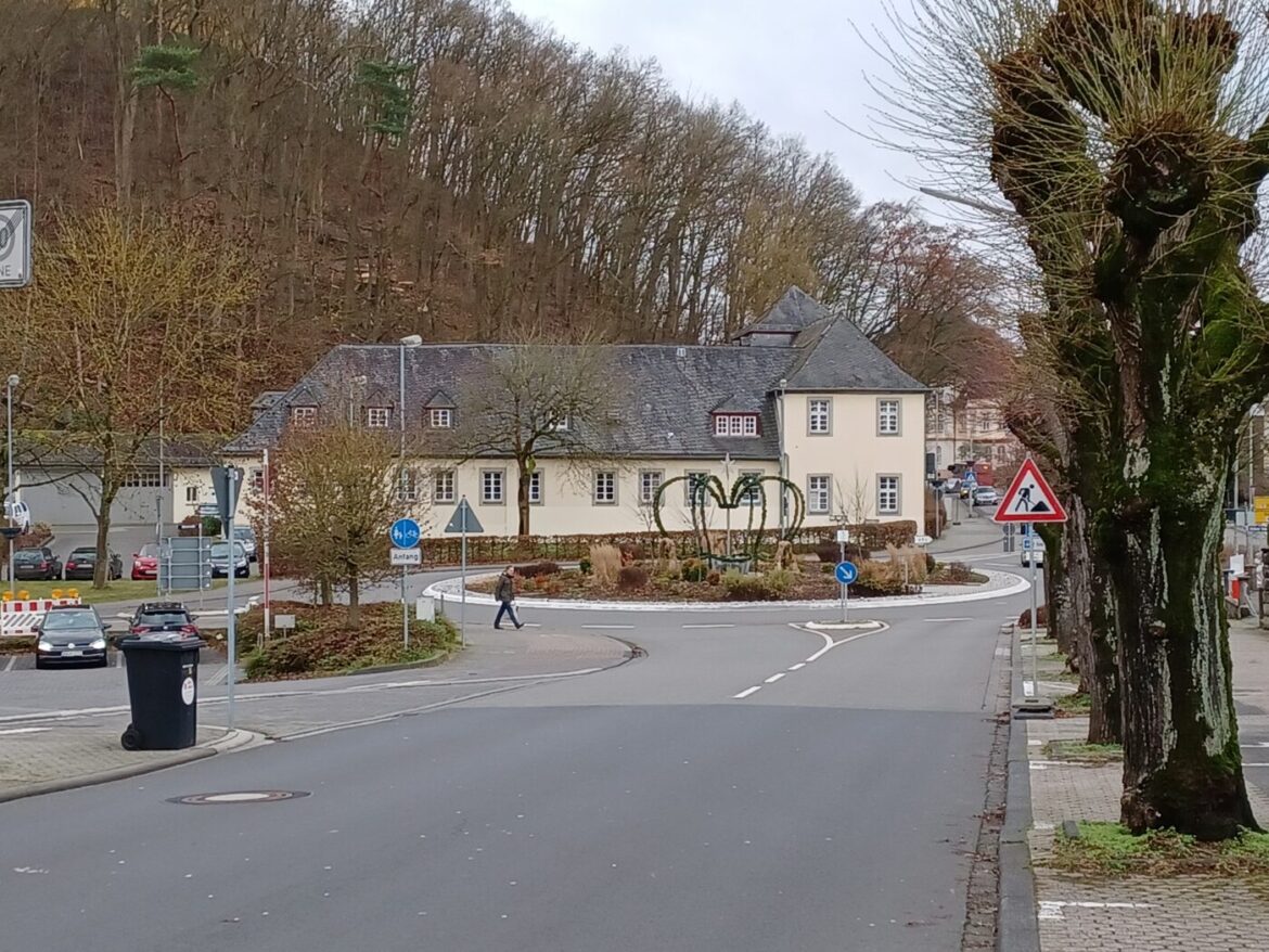 Straße mit Kreisverkehr und historischem Gebäude im Hintergrund.
