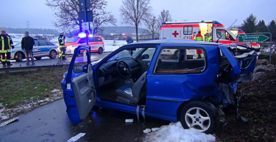 Verkehrsunfall mit beschädigtem blauen Auto und Rettungsfahrzeugen.