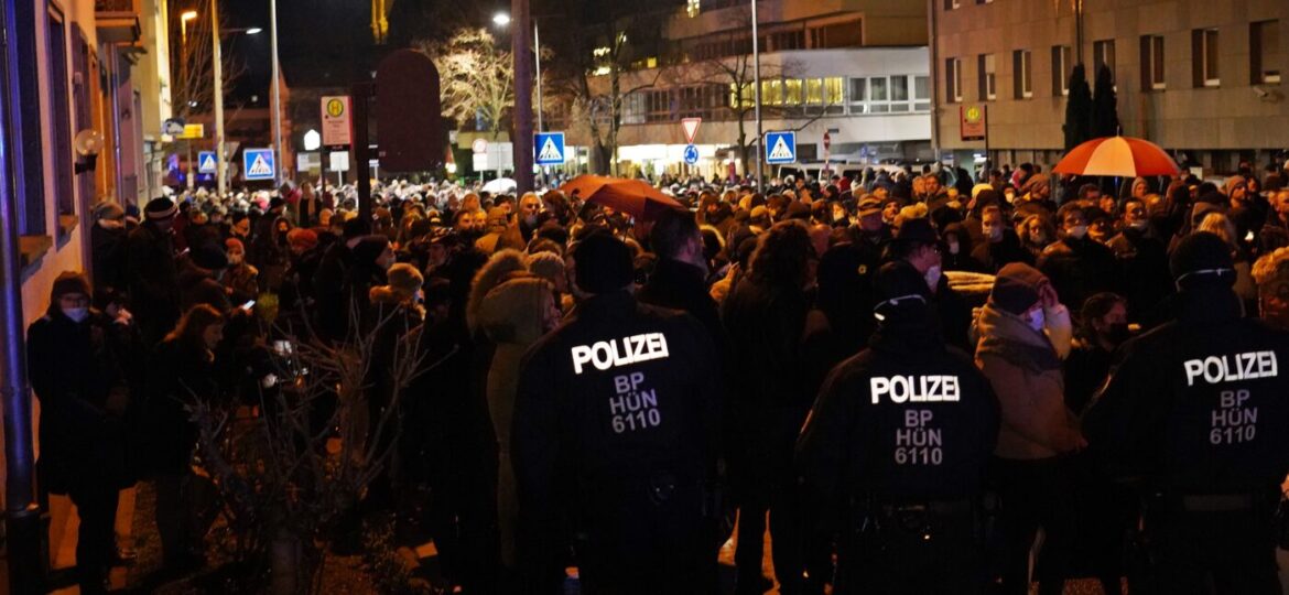 Menschenmenge bei Nacht mit Polizei im Vordergrund.