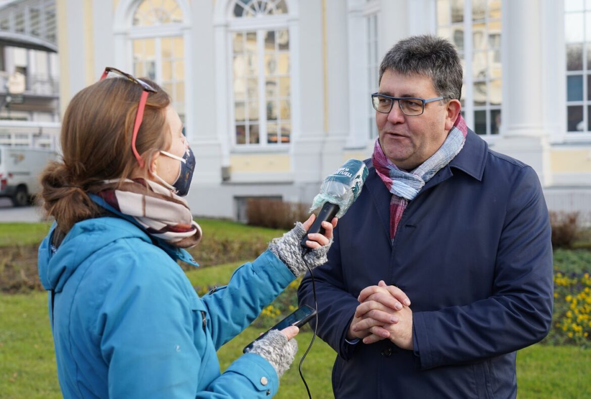 Reporter interviewt Mann vor einem historischen Gebäude.