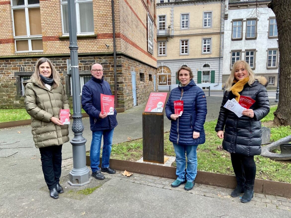 Vier Personen stehen mit Broschüren an einem Informationsschild.