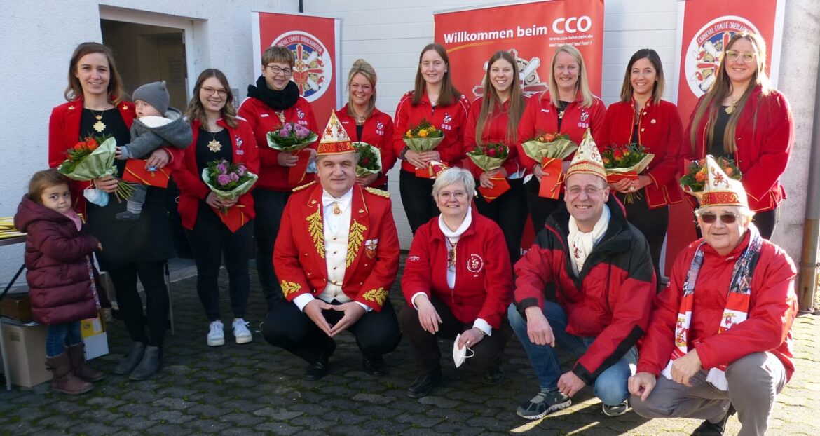 Gruppe von Menschen in roten Jacken mit Blumensträußen.