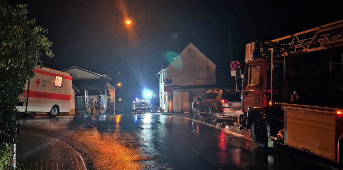 Nachtaufnahme eines Einsatzes von Rettungsfahrzeugen auf nasser Straße.