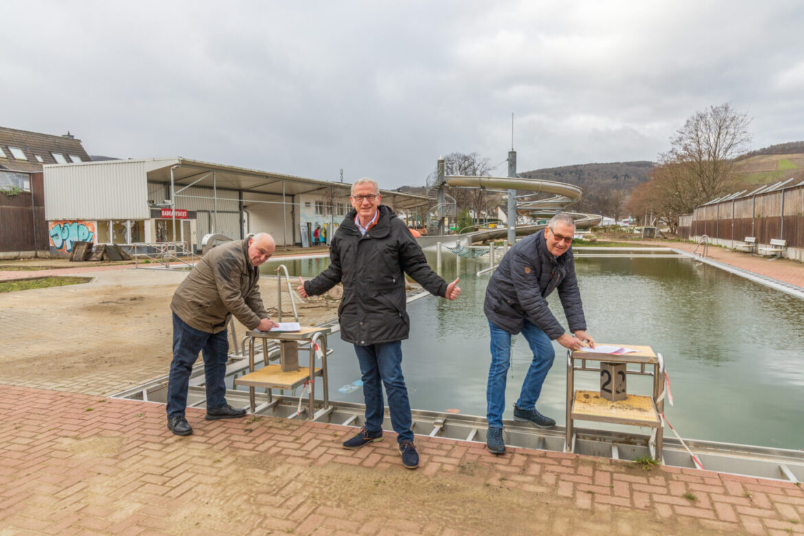 Drei Männer stehen am leeren Freibad Ahrweiler.