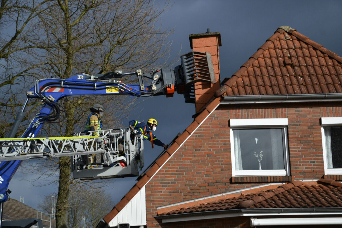 Feuerwehrleute auf einer Leiter inspizieren einen Schornstein.