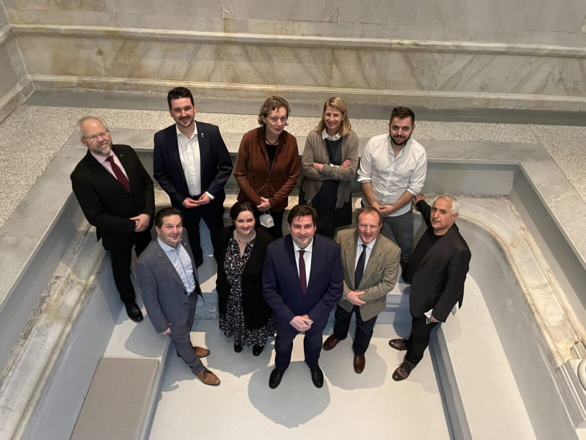 Gruppe von zehn Personen steht in einem Innenraum.