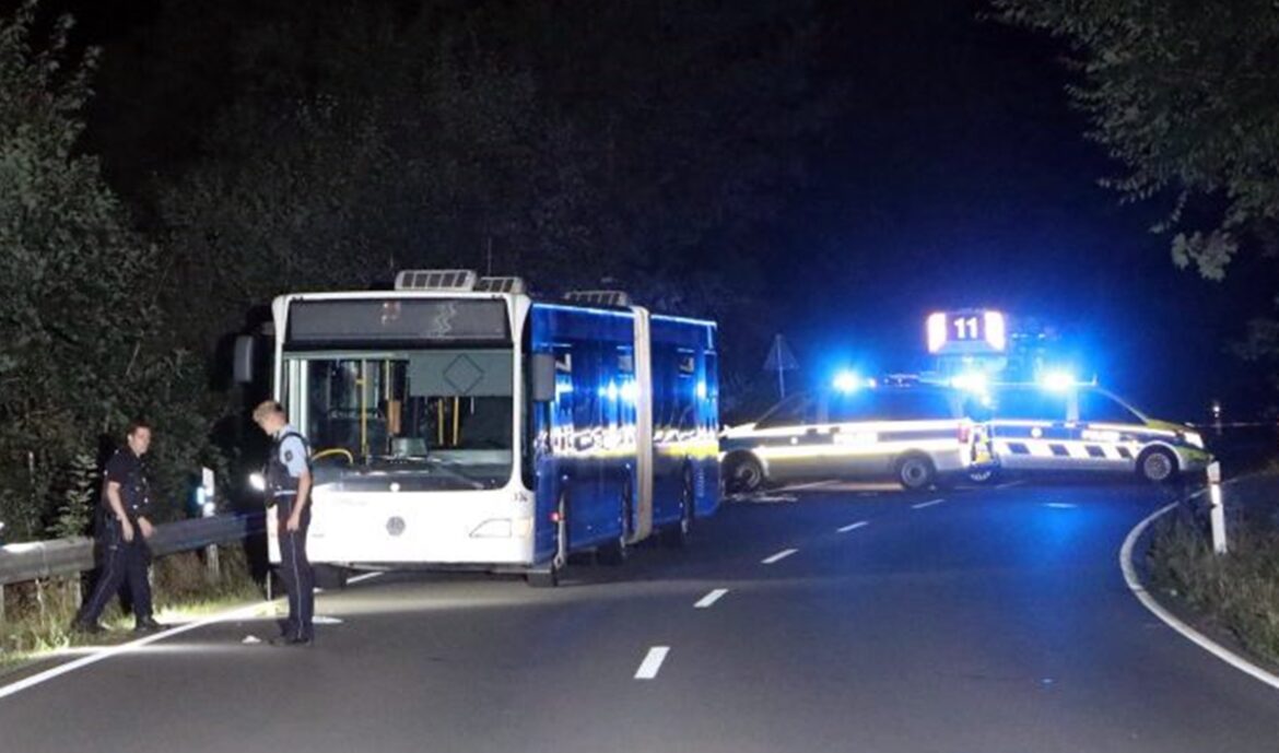 Messerangriff-Bus-Siege-Stadtfest-1 Polizisten sichern die Unfallstelle mit einem blauen Bus und zwei Polizeifahrzeugen bei Nacht.