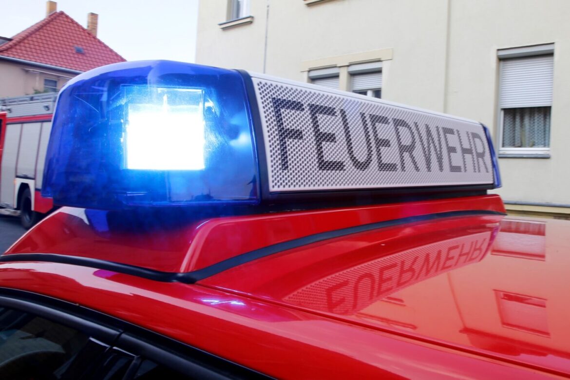 Blaulicht und "FEUERWEHR"-Schild auf dem Dach eines roten Feuerwehrfahrzeugs.