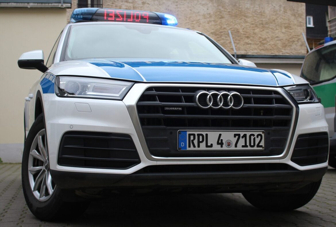 Polizeifahrzeug, Audi Q5, mit blauen Lichtern und standardmäßiger Lackierung, in einem Parkplatz.