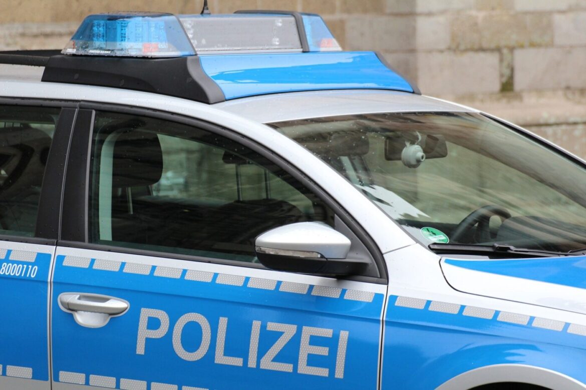 Blau-weißer Streifenwagen der Polizei mit eingeschaltetem Blaulicht, seitliche Ansicht.