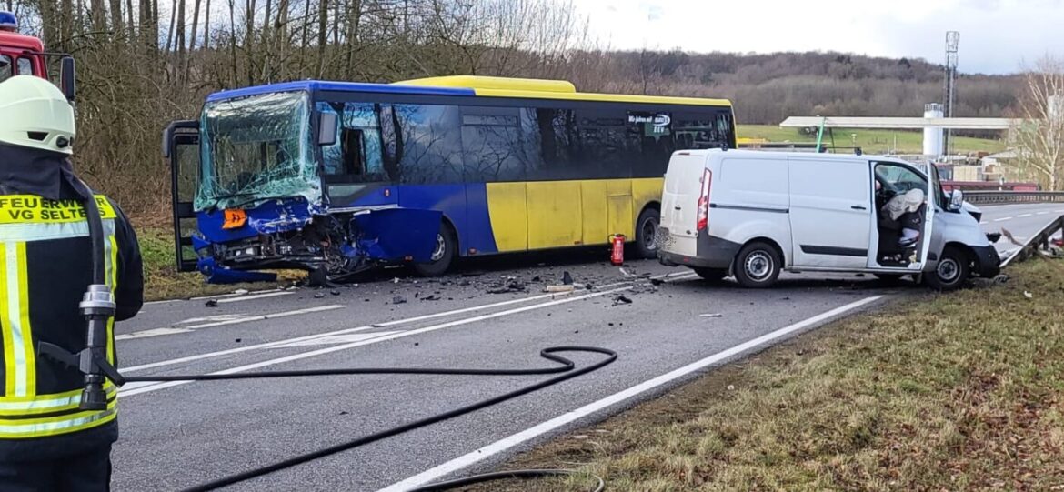 Unfall zwischen einem gelb-blauen Bus und einem weißen Lieferwagen, Feuerwehr im Einsatz.
