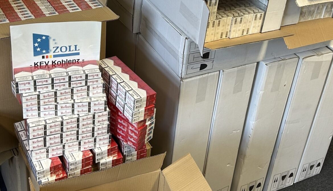 Stapel von Zigarettenschachteln, teilweise offen, mit Zollschild "Zoll KEV Koblenz" im Hintergrund.